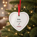 Personalized heart acrylic Christmas ornament with the name Jake, GOLFER, a golf flag and 2026, hanging by a red ribbon on a lit Christmas tree