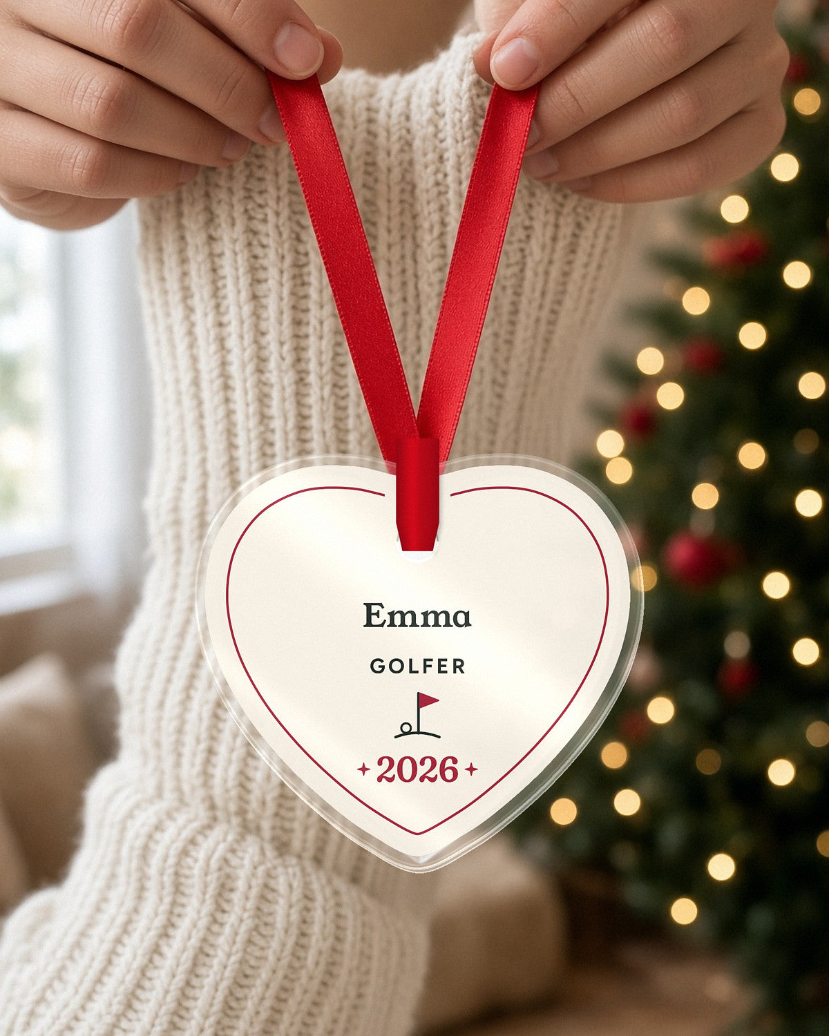Hands holding a personalized heart ornament by its red ribbon